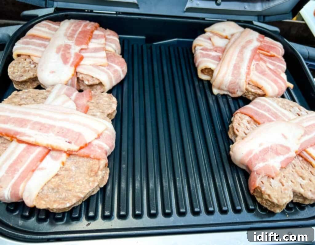Bacon-wrapped burger patties placed on the preheated Ninja Woodfire Grill.