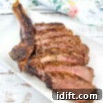 A tomhawk steak cooked on the Ninja Woodfire Grill. Sliced and served on a white platter.