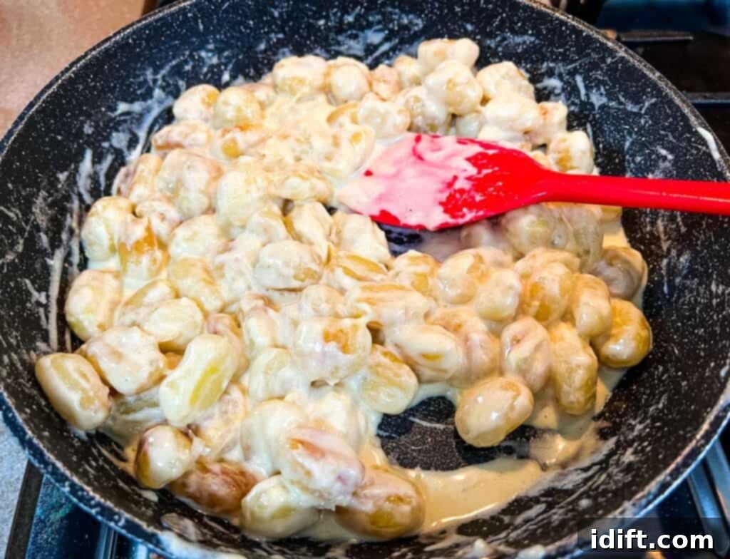 Stirring Gnocchi with Lemon Parmesan Sauce in a skillet as it thickens.