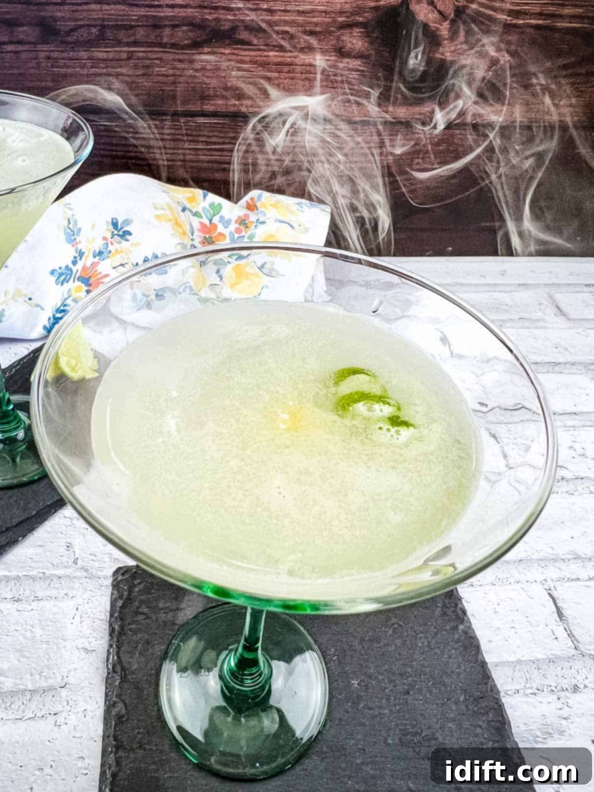 A mesmerizing Smoked Gimlet in a elegant glass, with delicate tendrils of smoke gracefully rising from its surface.
