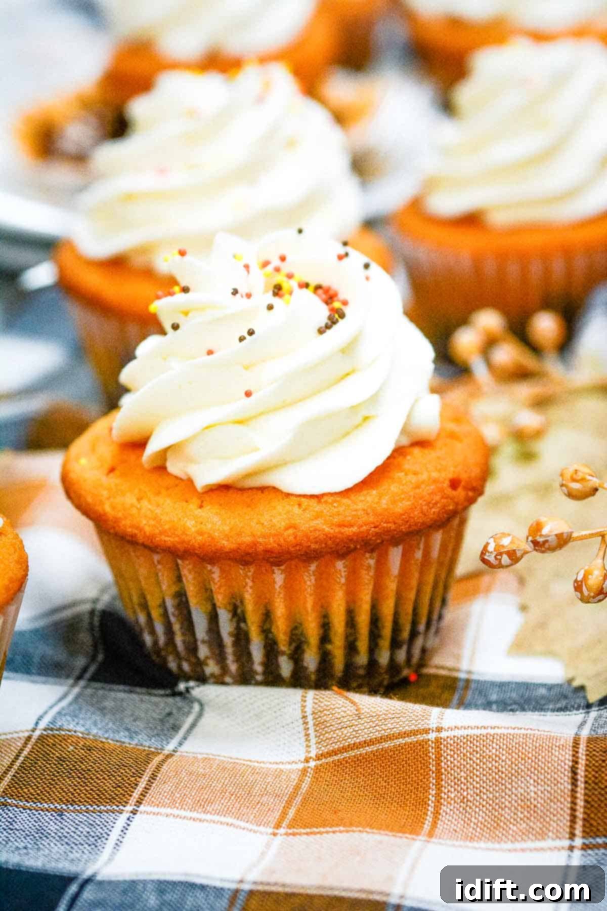 Autumn Fudgy Brownie Bites 2 Delightful Fall Brownie Cupcakes arranged beautifully on a rustic cloth, with more cupcakes artfully blurred in the background, ready for autumn celebrations.