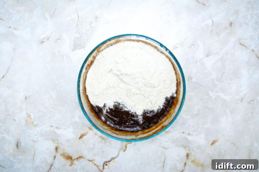 Autumn Fudgy Brownie Bites 9 All-purpose flour gently being folded into the brownie batter, ensuring a well-incorporated but not overmixed consistency.