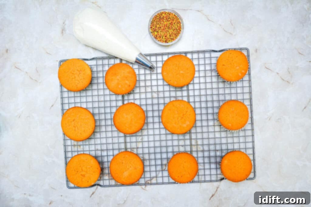 Autumn Fudgy Brownie Bites 14 Freshly baked Fall Brownie Cupcakes cooling on a wire rack, with a piping bag filled with icing in the background, ready for decoration.