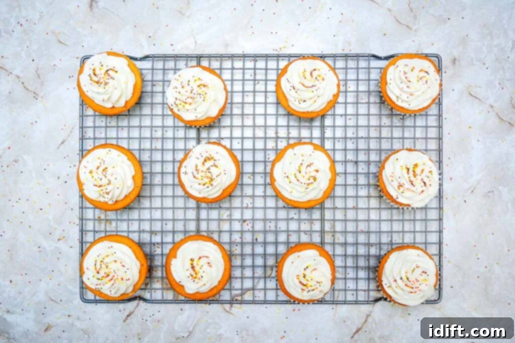 Autumn Fudgy Brownie Bites 4 Close-up of freshly iced Fall Brownie Cupcakes with vibrant orange frosting and decorative sprinkles, showcasing their festive appeal.