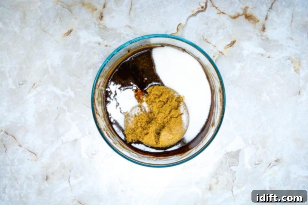 Autumn Fudgy Brownie Bites 7 Brownie batter in a bowl, with cocoa powder, instant coffee grounds, and sugars freshly incorporated, creating a rich dark mixture.