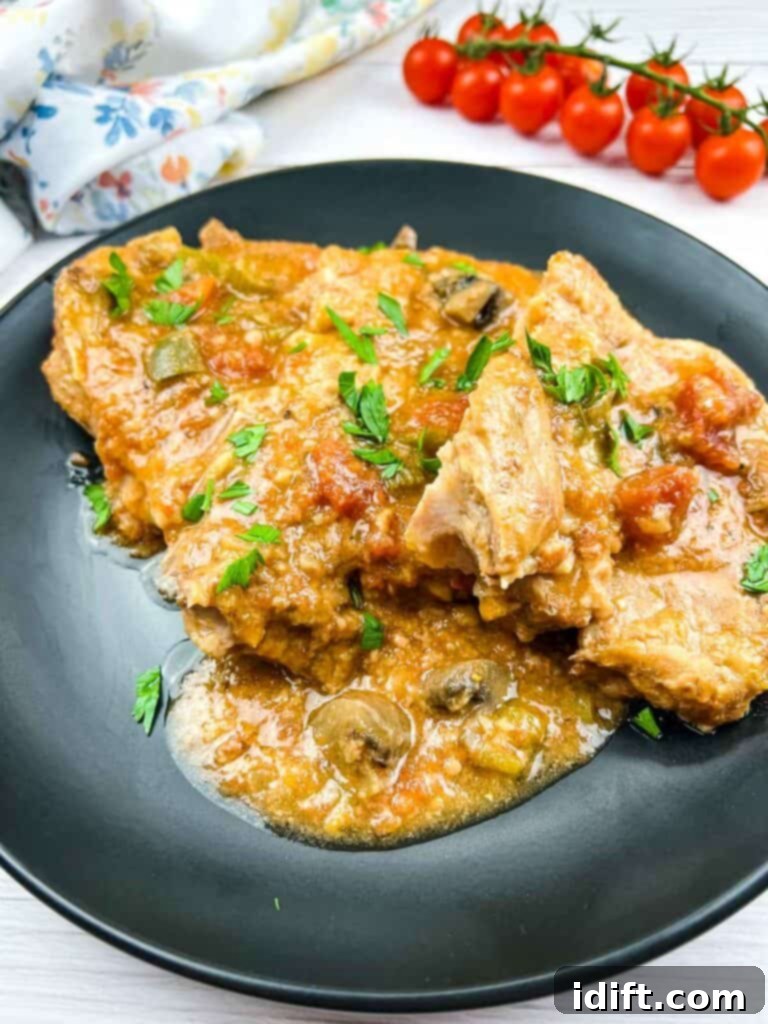 Slow Cooker Swiss Pork Chops on a black plate, showcasing the rich sauce and tender meat.