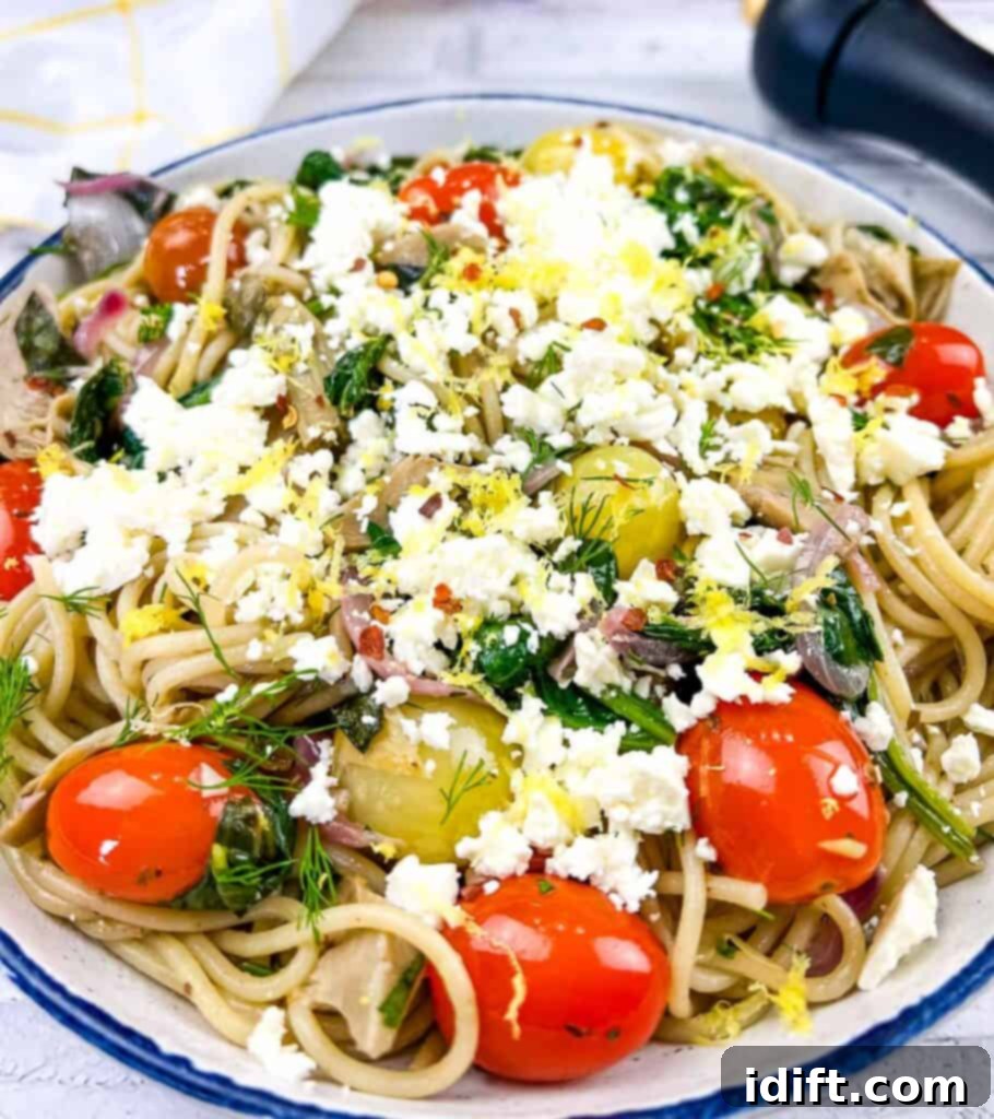 Mediterranean Spaghetti Delight 2 A vibrant bowl of Greek Spaghetti, showcasing pasta intertwined with cherry tomatoes, artichoke hearts, spinach, and crumbled feta cheese.