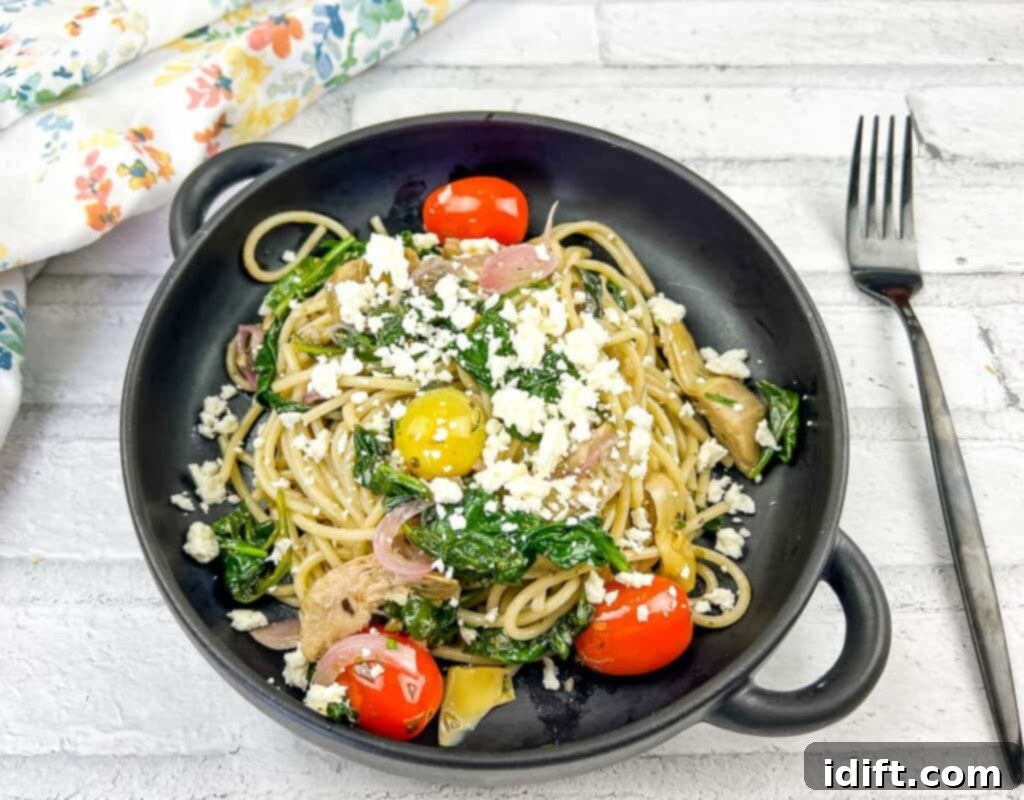 Mediterranean Spaghetti Delight 3 A top-down shot of a delicious Greek Spaghetti dish in a black bowl, garnished with fresh herbs and feta cheese.