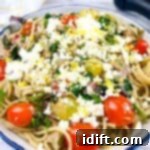 Mediterranean Spaghetti Delight 9 A vibrant bowl of Greek Spaghetti, showcasing pasta intertwined with cherry tomatoes, artichoke hearts, spinach, and crumbled feta cheese.