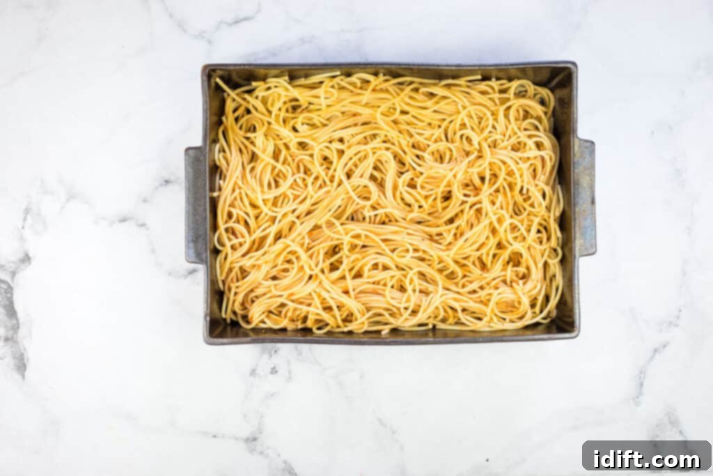 Priceless Pasta Bake 13 Pasta with sauce in a square pan on a marble countertop.