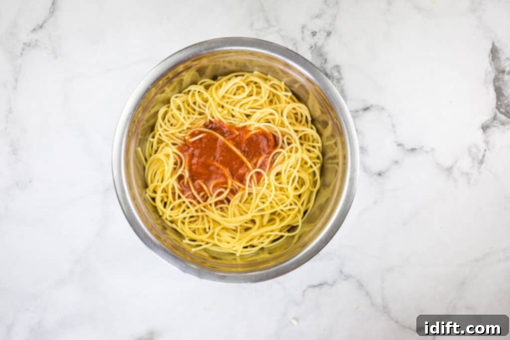 Priceless Pasta Bake 7 A bowl of spaghetti with sauce on a marble table.