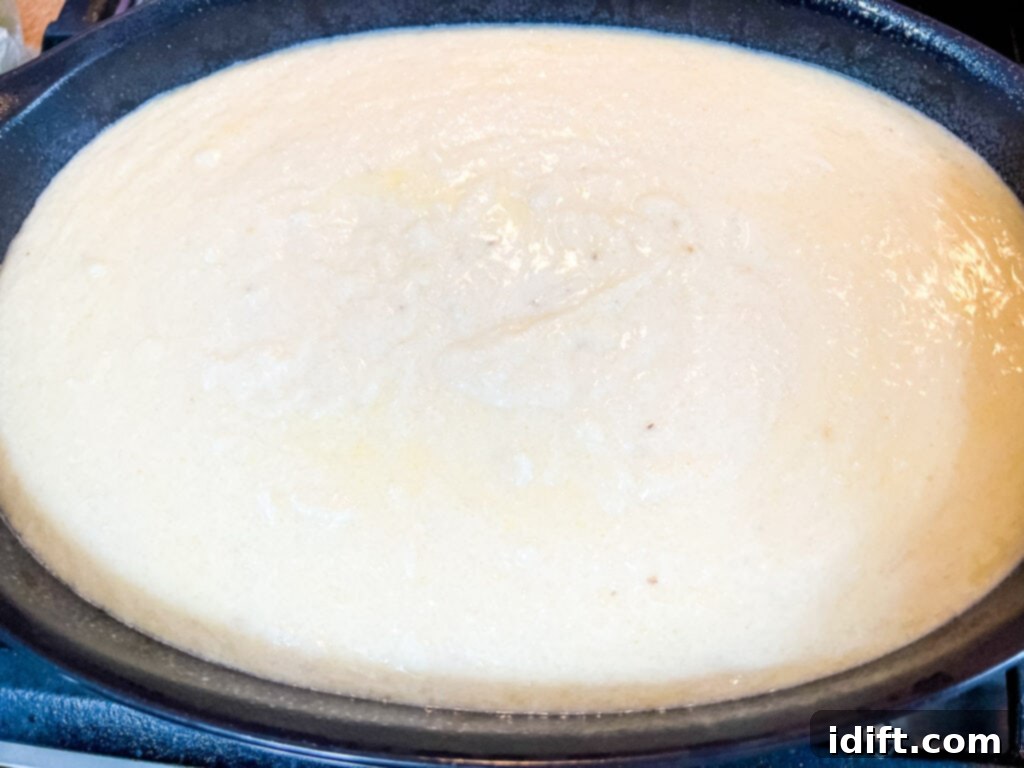 Comforting Baked Shrimp and Grits Casserole 12 The creamy grits mixture being transferred into a casserole dish, ready for the oven.