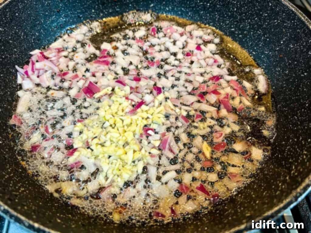 Comforting Baked Shrimp and Grits Casserole 16 A frying pan containing sautéed onions and garlic in bacon fat.