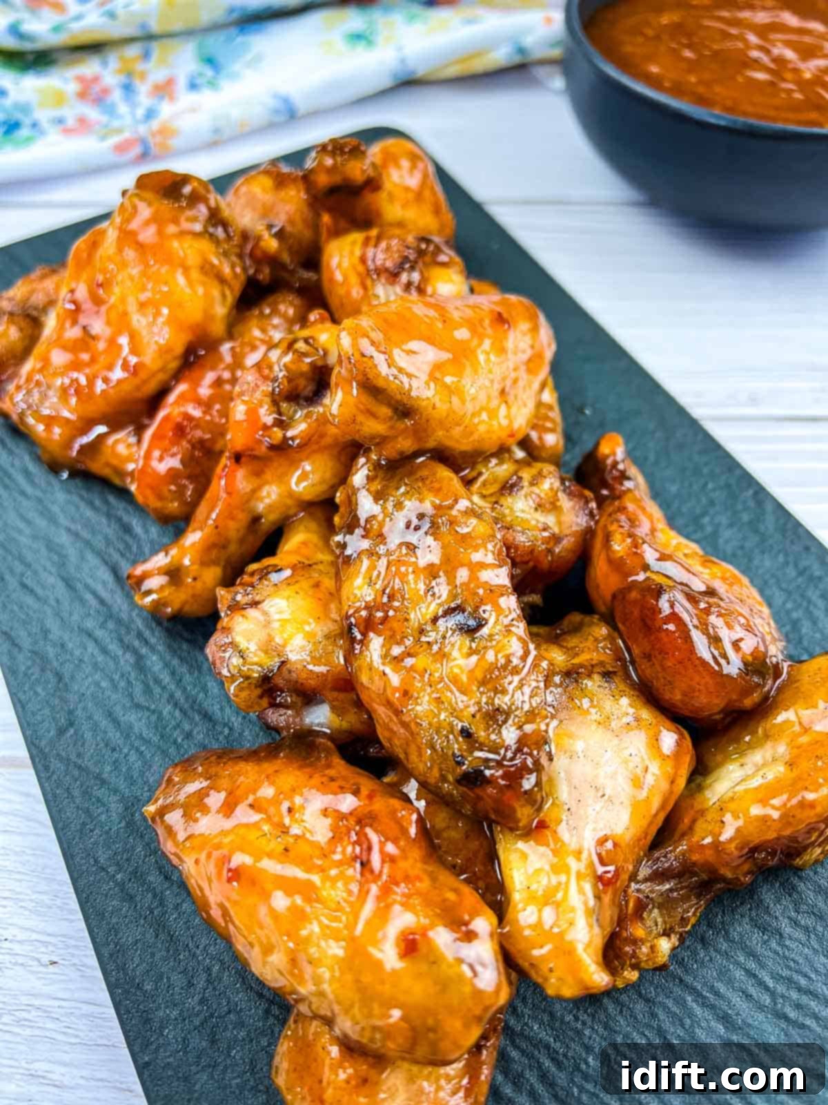 Plate of perfectly smoked peach-chipotle chicken wings with dipping sauce on the side.