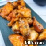 Chicken wings on a plate with sauce on the side.