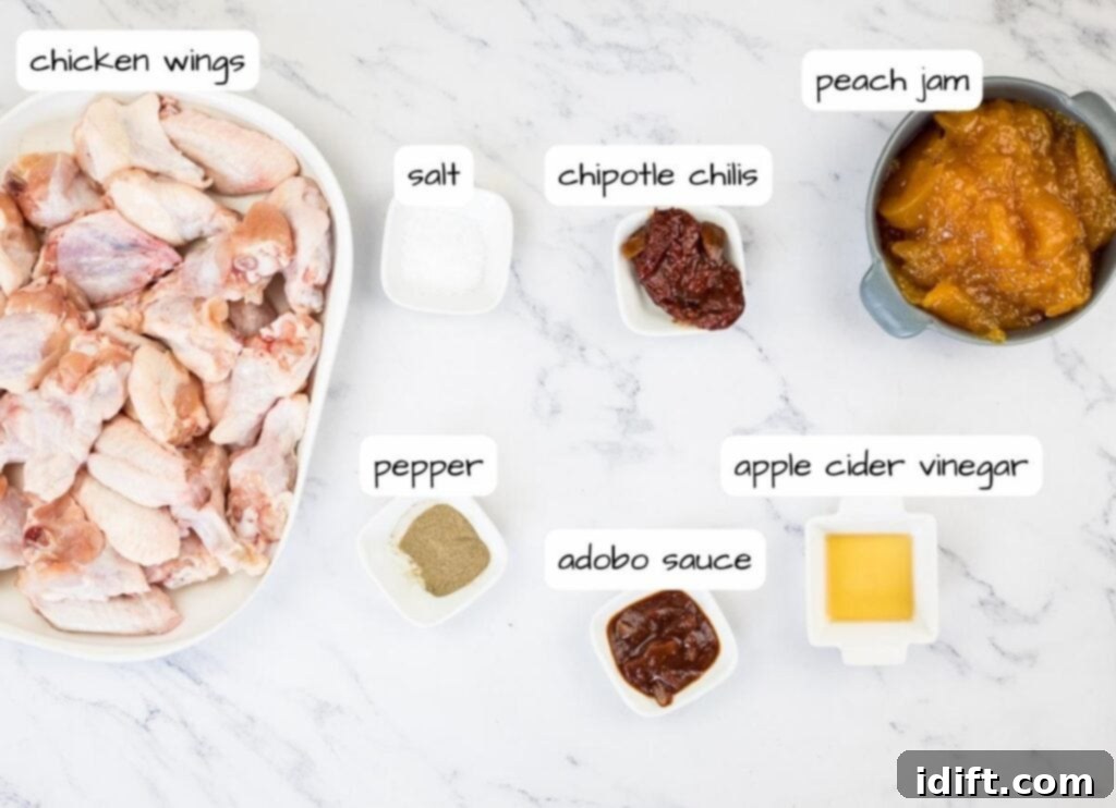Carefully arranged chicken wings, spices, peach jam, chipotle in adobo, and apple cider vinegar on a marble table, ready for cooking.