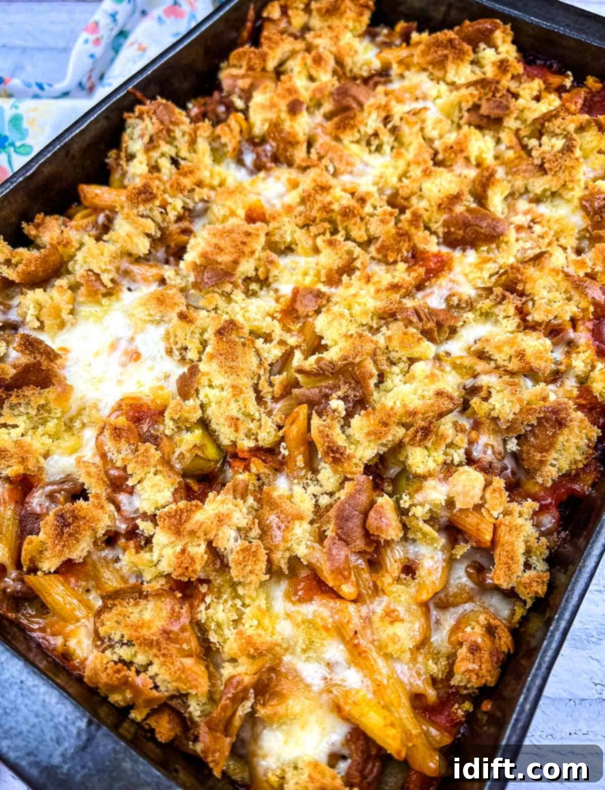 Hearty Sloppy Joe Noodles 2 A bubbling hot casserole dish filled with savory Sloppy Joe pasta, topped with melted golden cheese and a crispy bun topping, ready to be served.