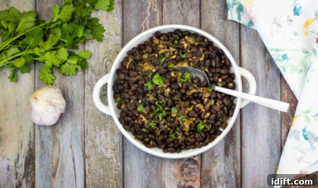 Black beans in a white bowl on a wooden table.