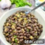 Black beans in a white bowl with garlic and parsley.