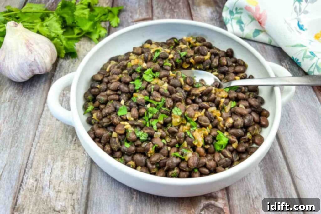 Black beans in a white bowl on a wooden table.