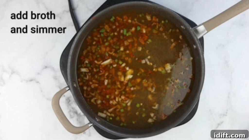 Chicken broth being poured into a pot of sautéed ingredients.
