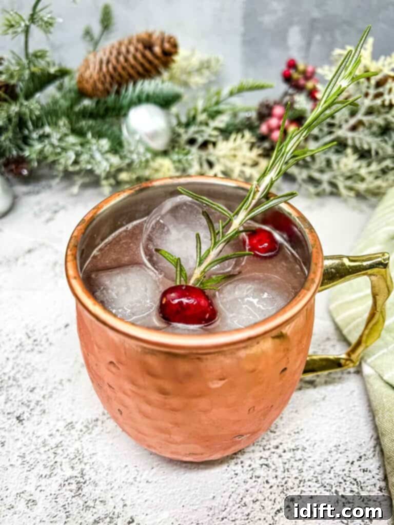 A copper moscow mule with cranberries and a sprig of rosemary.