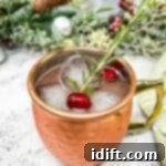 A copper moscow mule with cranberries and a sprig of rosemary.