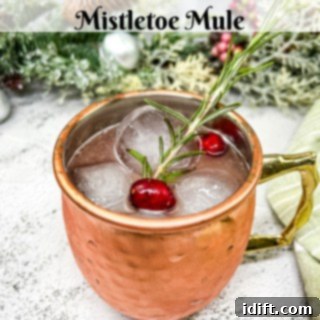 Ruby Cranberry Elixir 5 Mistletoe mule in a copper mug with cranberries and sprigs of rosemary.