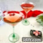 Ruby Cranberry Elixir 6 Two martinis with cranberries and decorations on a table.