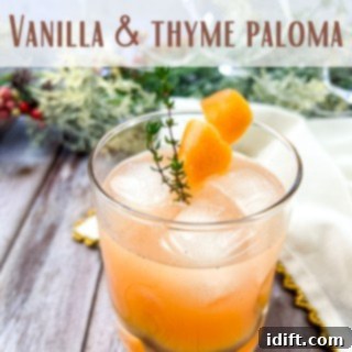 A elegant Vanilla and Thyme Paloma cocktail in a glass, garnished with a sprig of fresh thyme.