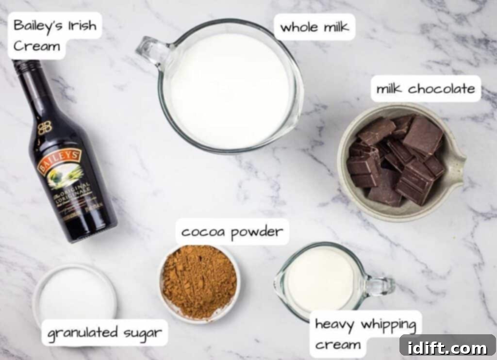 Essential ingredients for creamy Baileys hot chocolate are arranged on a white surface.