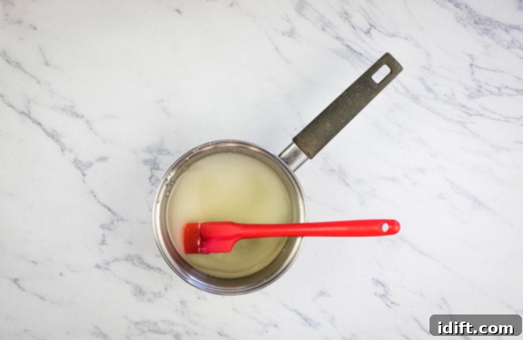 A saucepan with sugar syrup cooking on the stove.