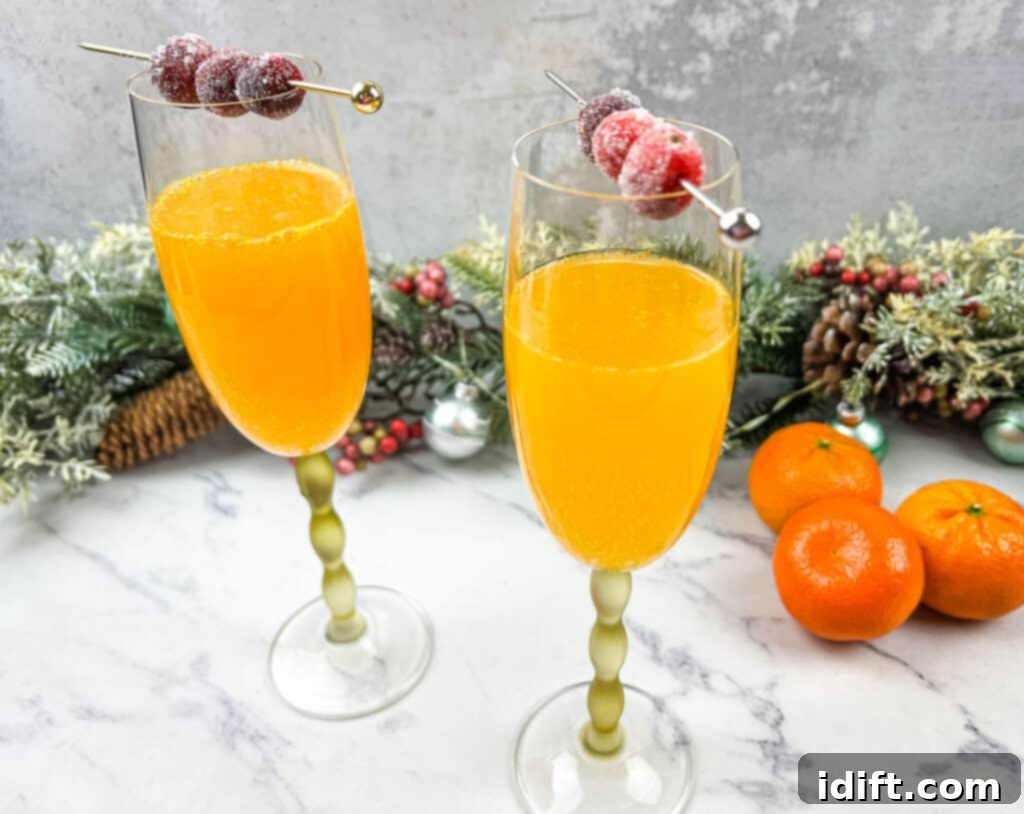 Two glasses of Christmas Mimosas with oranges and cranberries, festive and inviting.