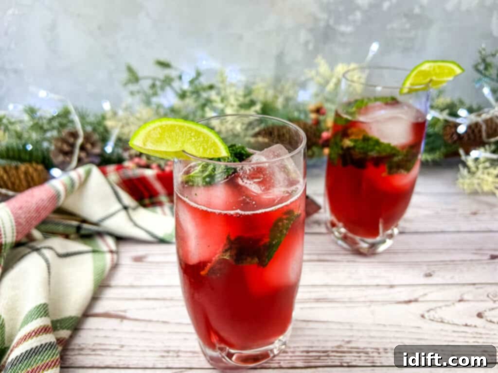 Two glasses of Pomegranate Mojitos on a wooden table, featuring beautiful garnishes.