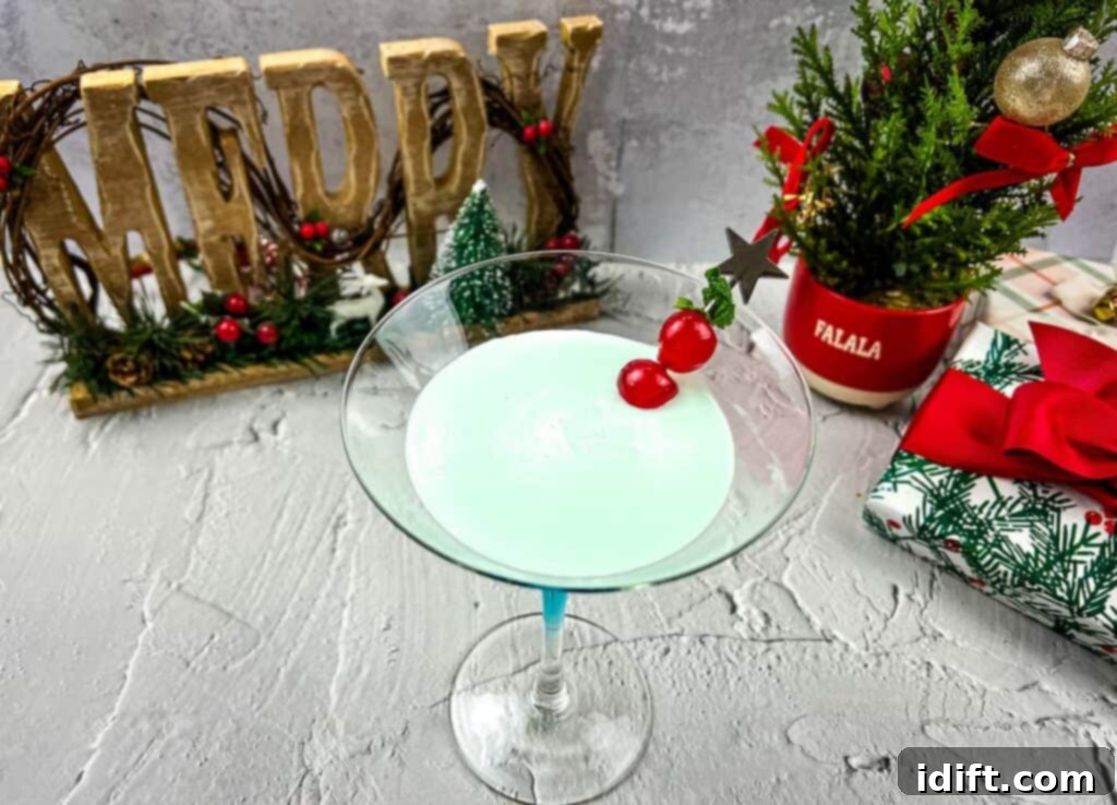 A beautifully garnished Whoville Martini, vibrant blue, with a single cherry on top, ready for a festive celebration.
