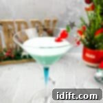 A martini in a glass with a christmas tree in the background.