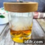 A glass of whiskey with a candle in it.