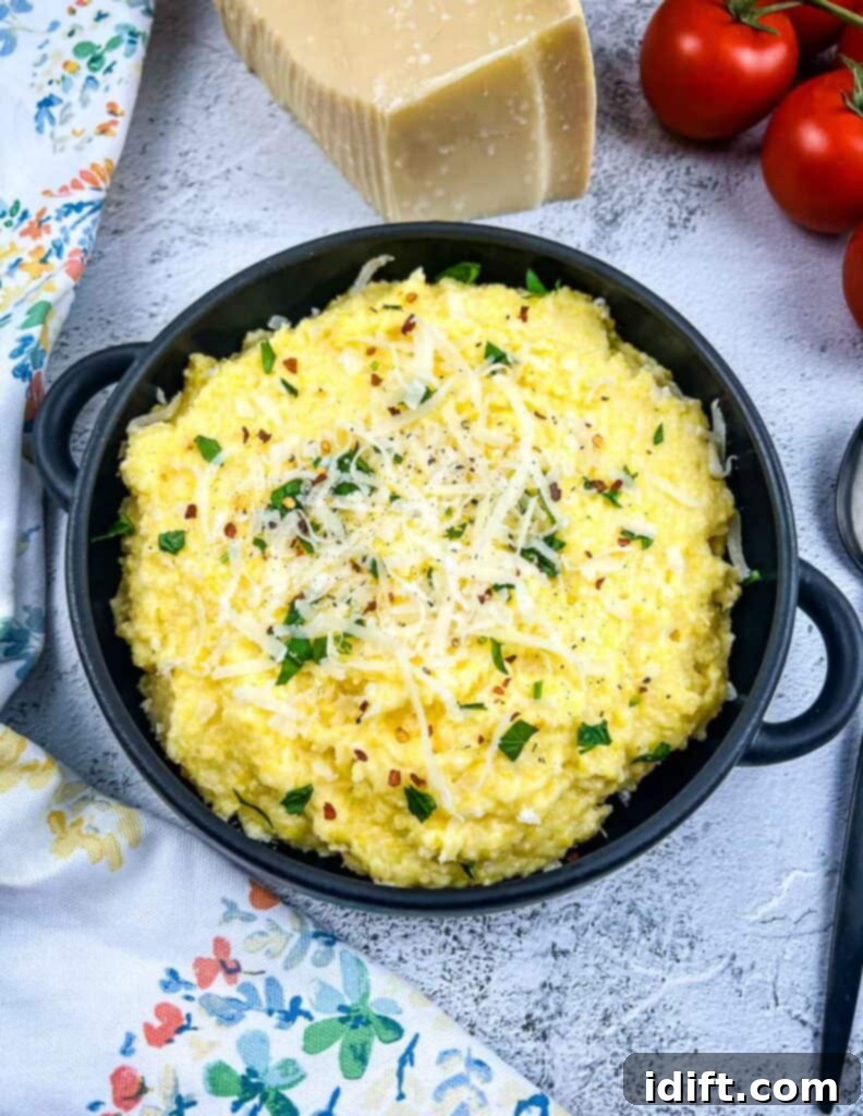 A bowl of polenta with mascarpone with tomatoes in the background.