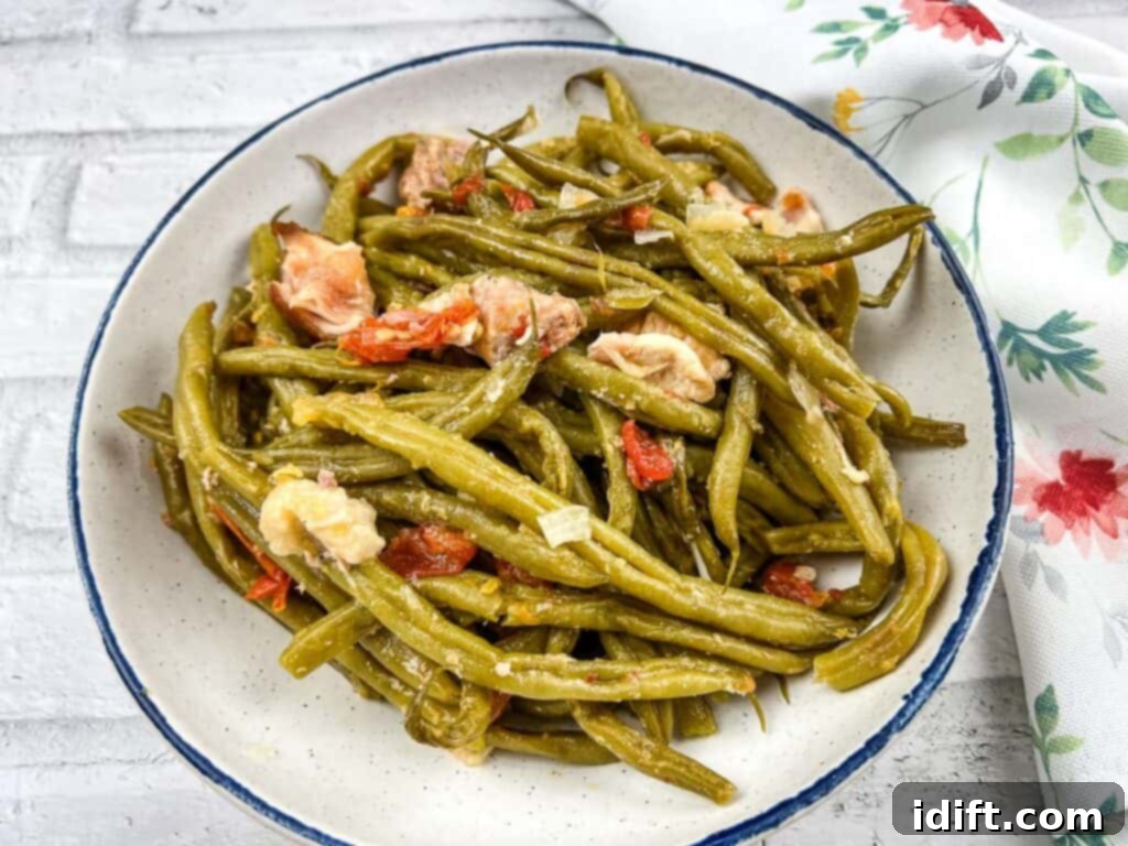 Green beans in a white bowl with chopped tomatoes, ready to be served as a delightful side.