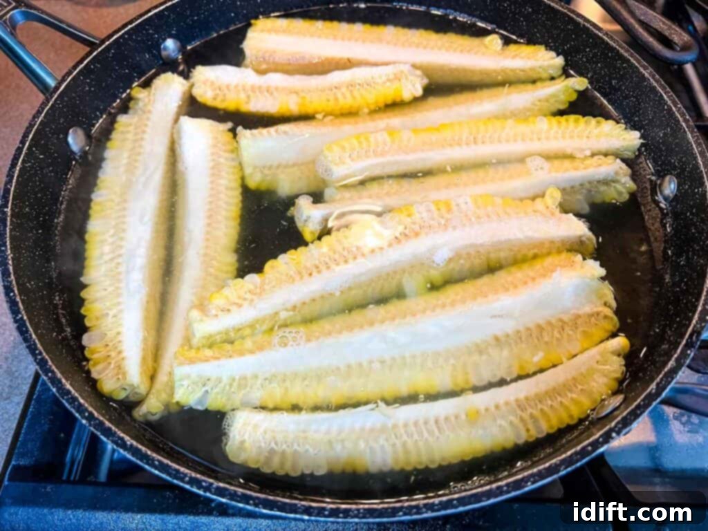 Corn ribs boiling gently in a pot of water on the stove.
