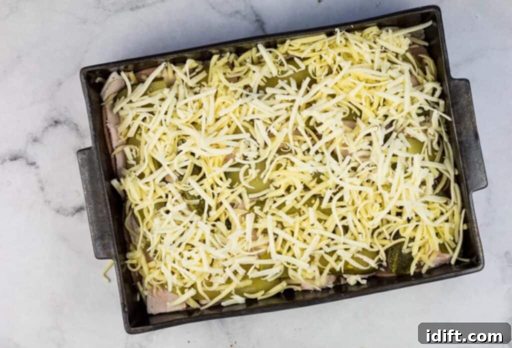 Cubano Casserole 13 A baking dish filled with layers of cheese and meat, ready for the next step in the casserole preparation.