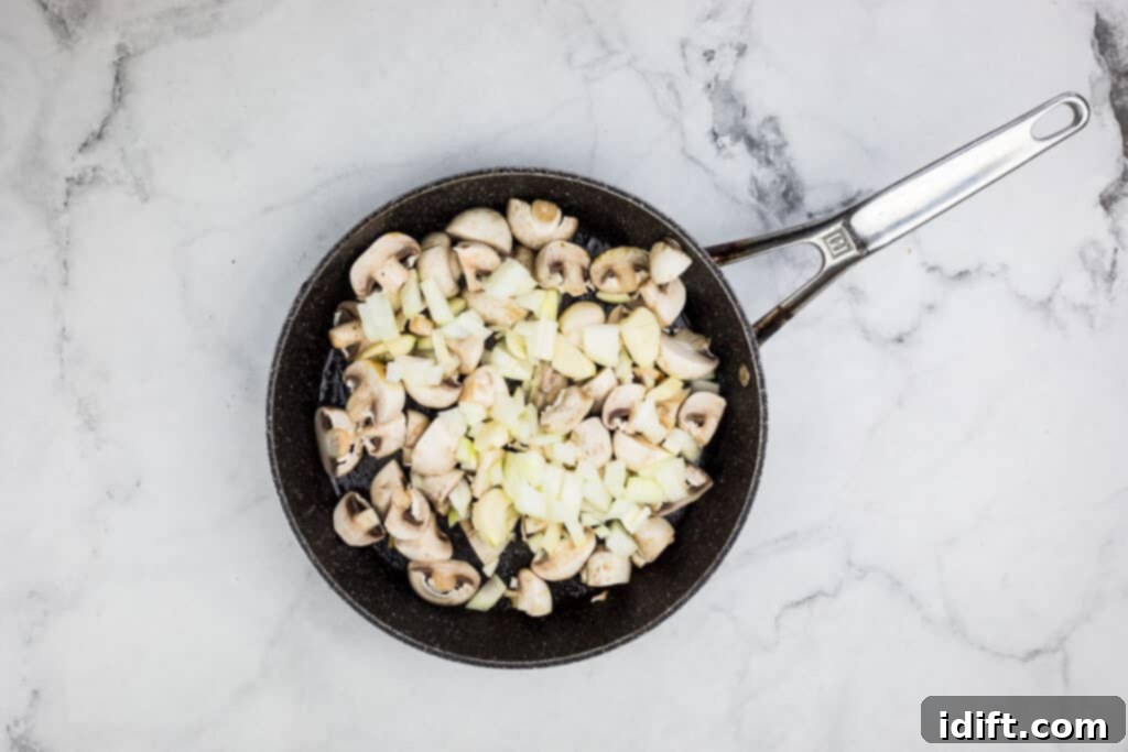 A frying pan filled with mushrooms and onions cooking.