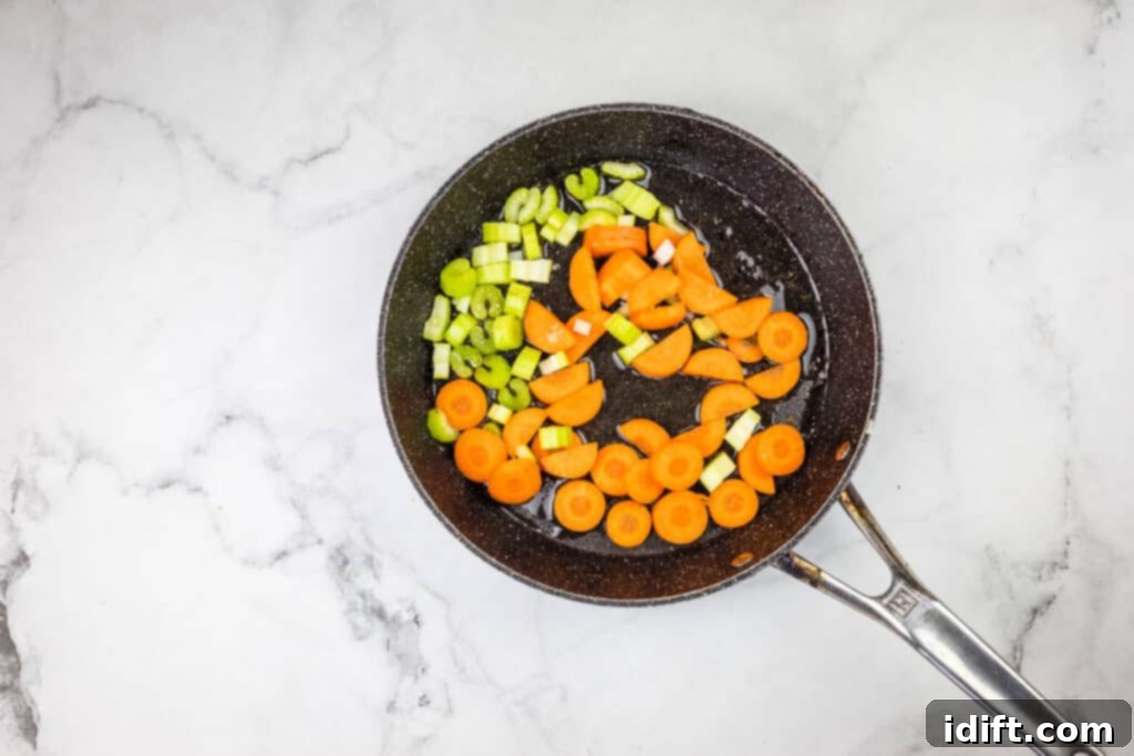 Carrots and celery sautéing in a frying pan.