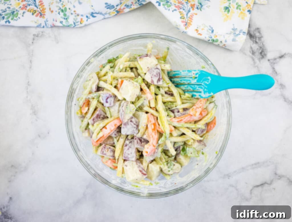 Sun-Kissed Potato and Golden Bean Salad 11 A bowl of Yellow Bean & Potato Salad with a blue spatula.