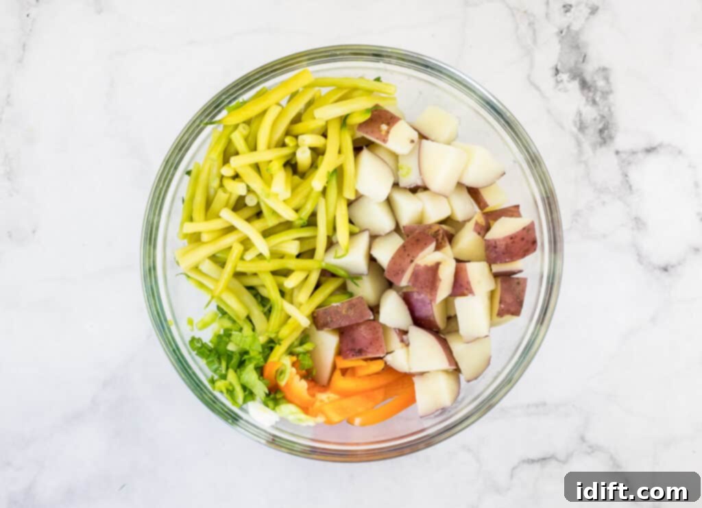 Sun-Kissed Potato and Golden Bean Salad 10 Green beans, potatoes and bell pepper in a glass bowl.