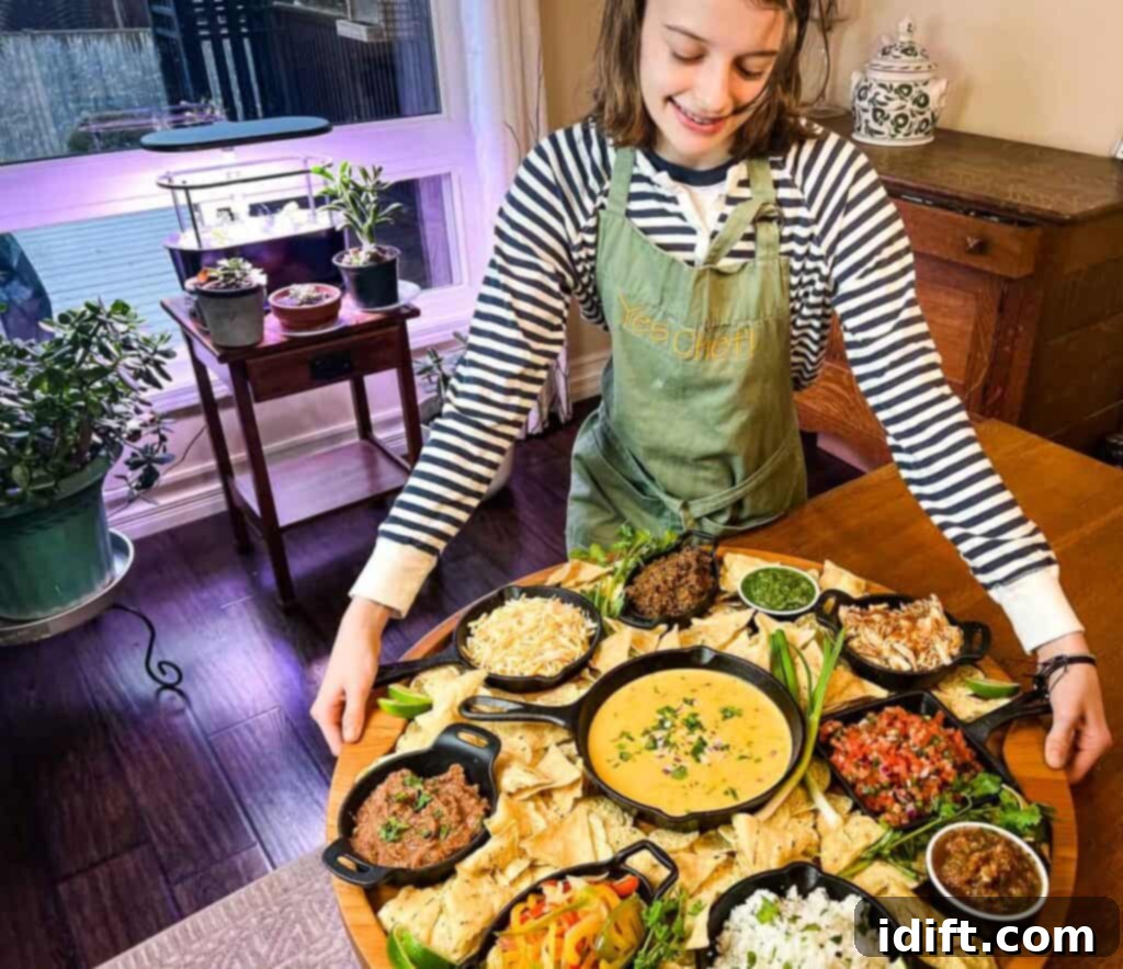 Mega Nacho Spread 3 A woman in an apron stands proudly in front of a generously filled Nacho Snack Board, showcasing the vibrant array of ingredients.