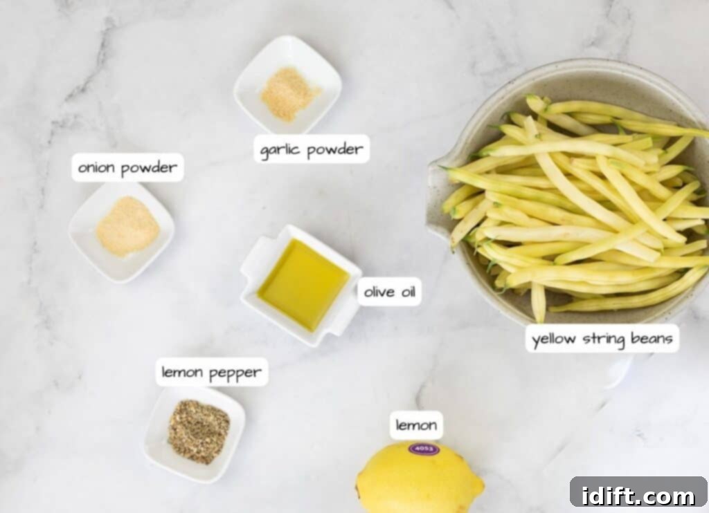 Ingredients for lemony green beans laid out on a marble table, including yellow beans, lemon pepper, garlic powder, onion powder, and olive oil.