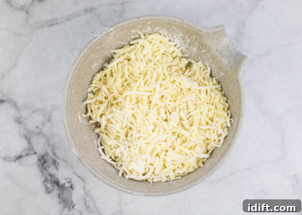 Pizza Fondue A Savory Spin on Classic Fondue 7 Finely shredded fontina and mozzarella cheese are tossed with cornstarch in a bowl on a marble countertop.