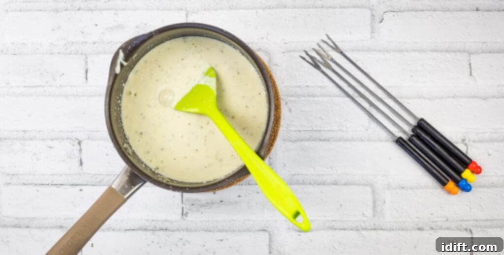 Pizza Fondue A Savory Spin on Classic Fondue 8 A frying pan showing creamy cheese sauce with a hint of tomato, being stirred by spatulas on a stovetop.