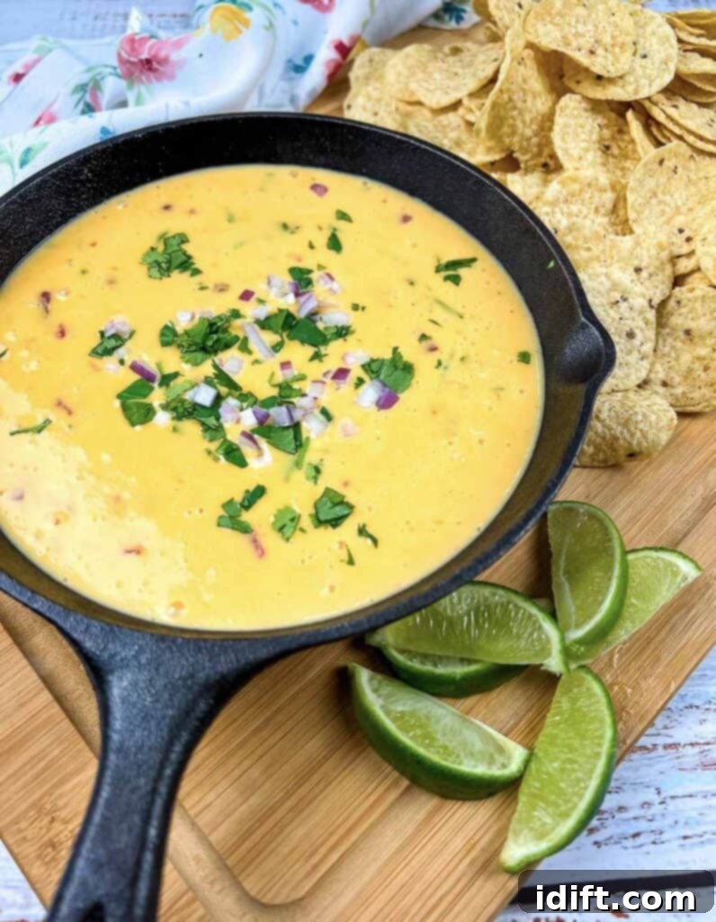 Mexican cheese dip in a cast iron skillet with tortilla chips.